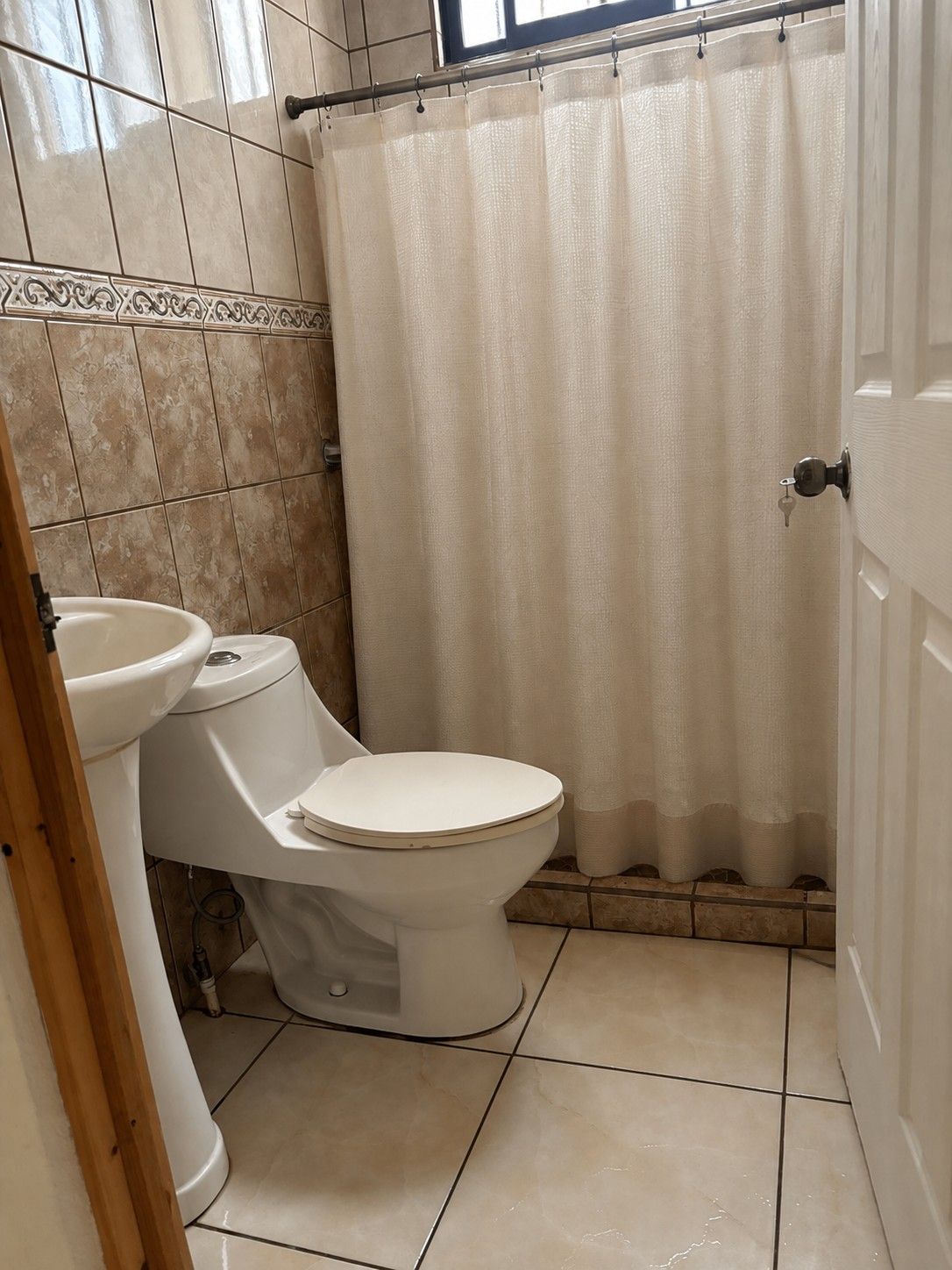 Kylpyhuone, jossa on wc, pesuallas ja suihkuverho.