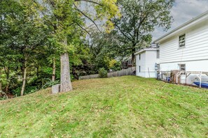 A residential backyard with a grassy lawn, a wooden fence, and a white house.