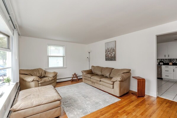 A spacious living area with a large sofa set, a coffee table, and a view of the kitchen.