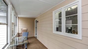 A corridor with beige siding walls, a glass table with chairs, and a window with a view.
