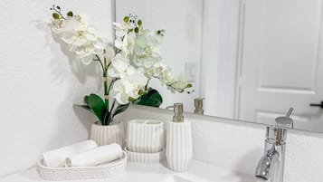 Un baño con un lavabo blanco, un espejo y una toalla blanca.