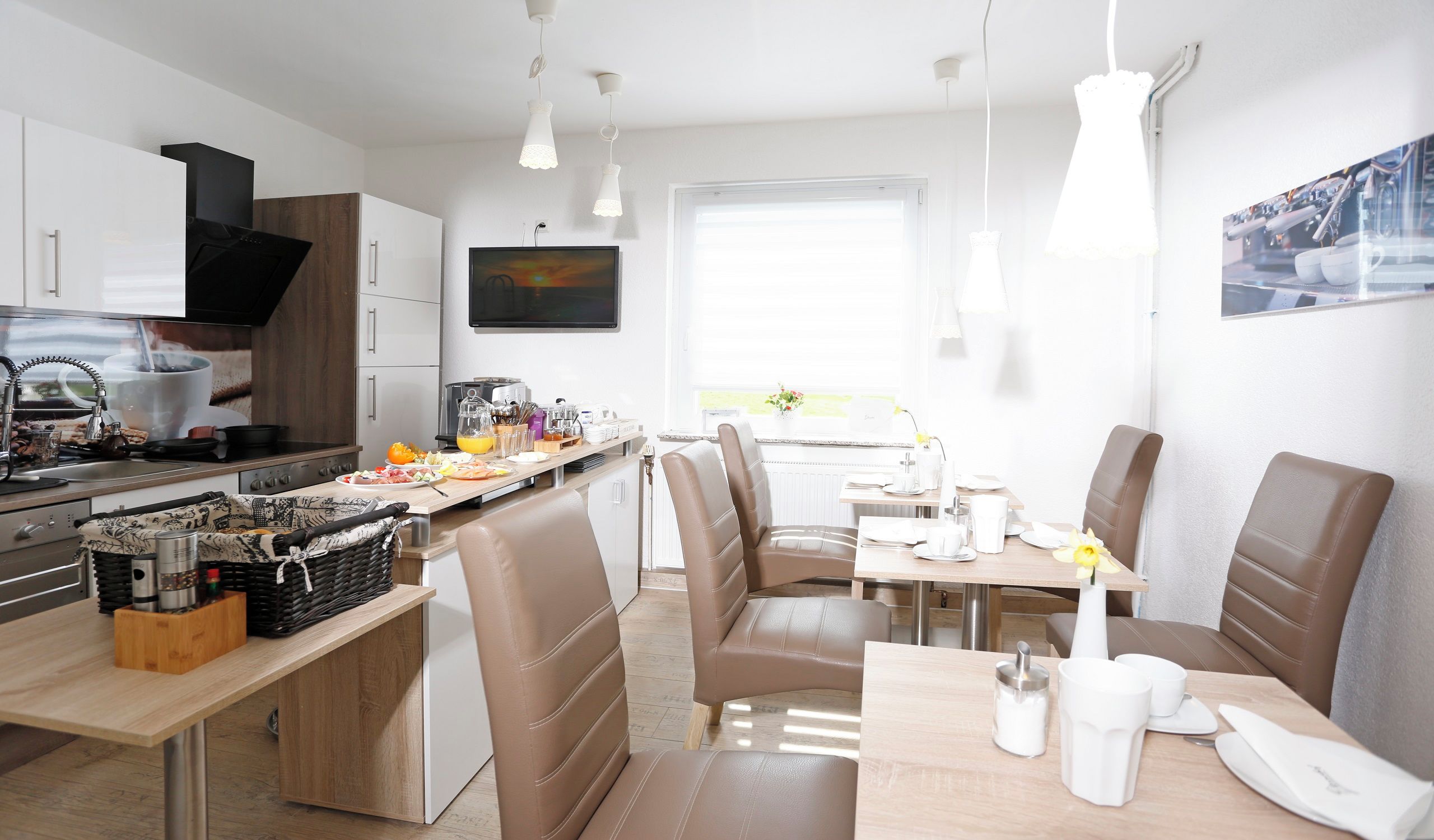 Eine moderne Küche mit Essbereich, inklusive einer Frühstückstheke, Sitzgelegenheiten und einem Fernseher.