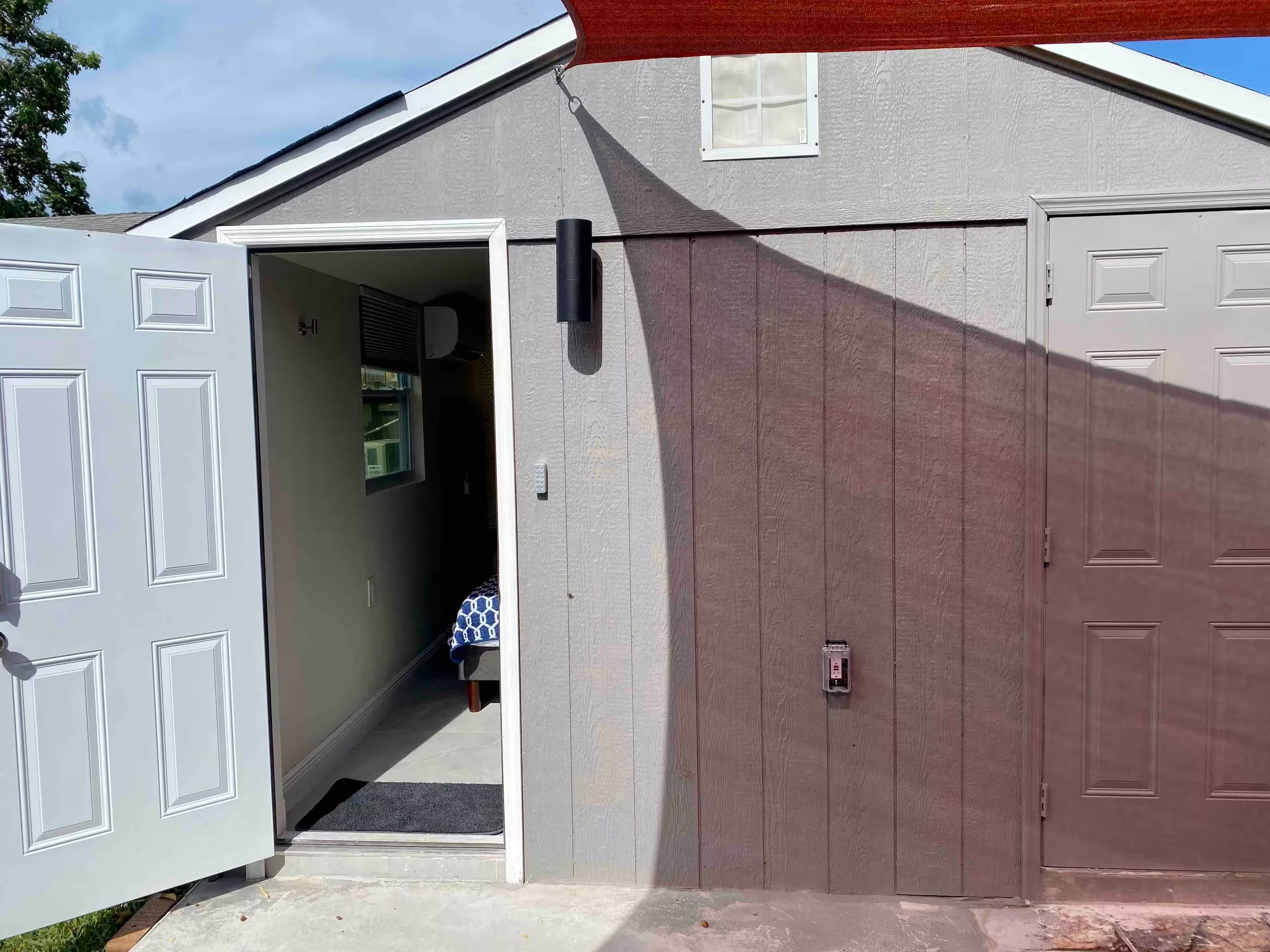 A garage with two white doors, a small window, and a doorbell.