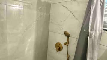 Un baño con ducha, inodoro y piso de baldosas.
