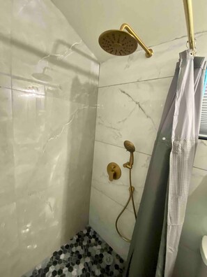 Un baño con ducha, inodoro y piso de baldosas.