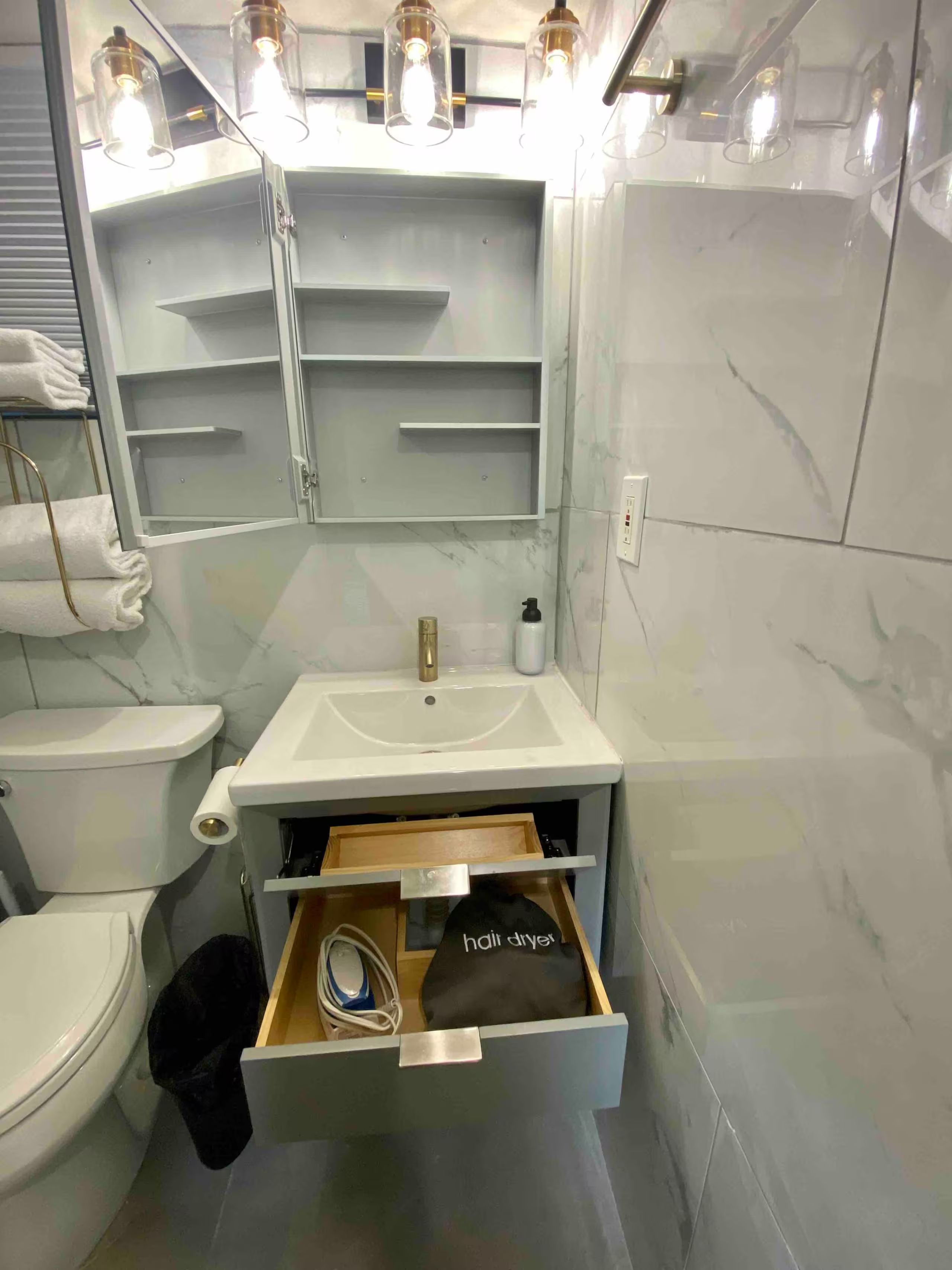Un baño con lavamanos blanco, inodoro, toallero y espejo.