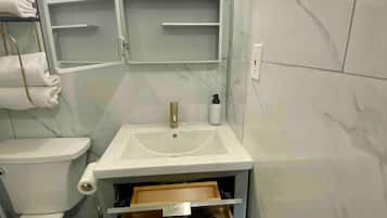 Un baño con lavamanos blanco, inodoro, toallero y espejo.