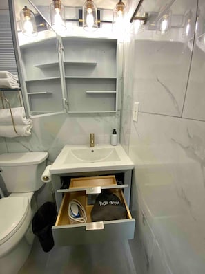 A bathroom with a white sink, a toilet, a towel rack, and a mirror.