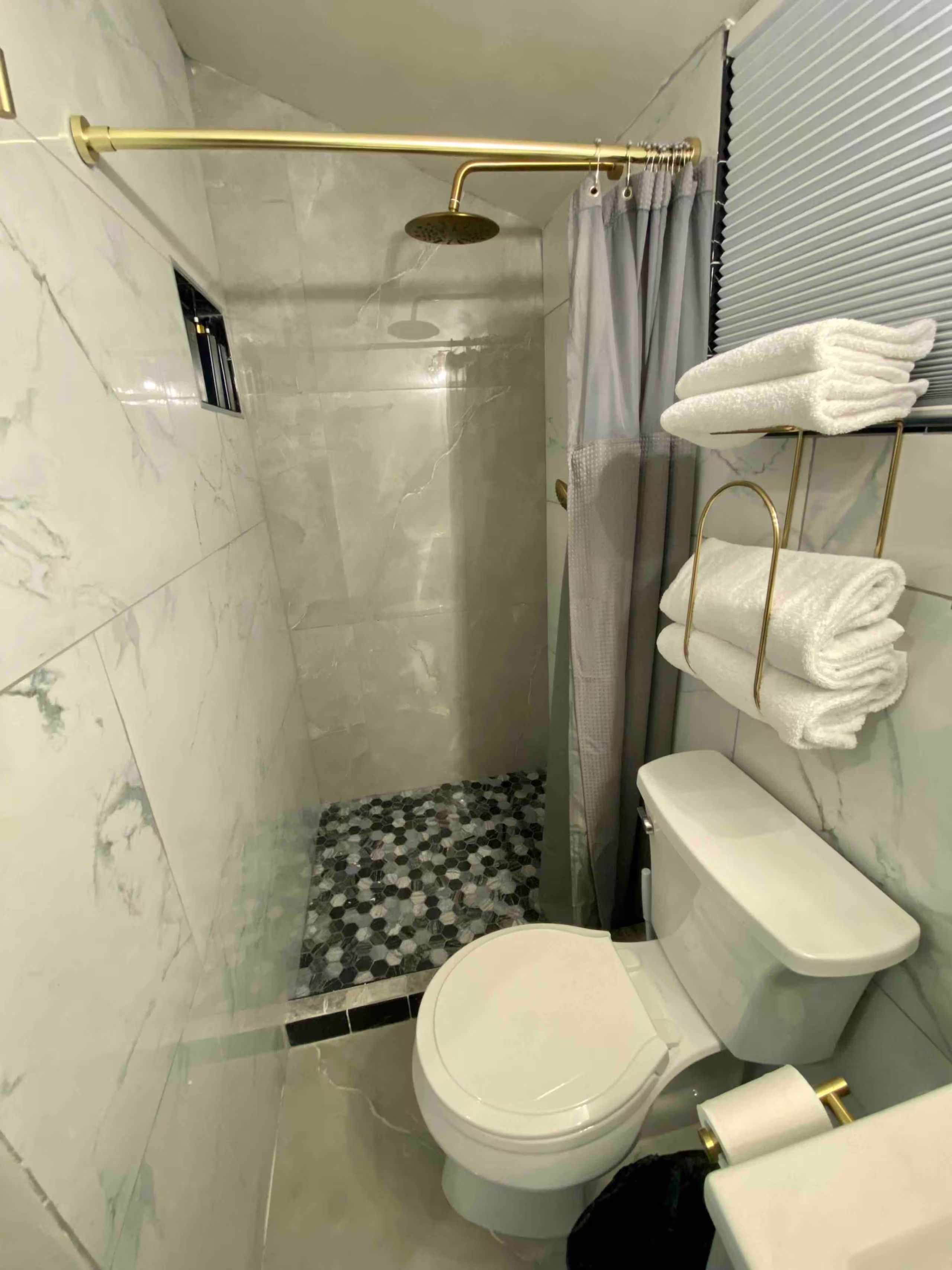 Een badkamer met douche, toilet en handdoekrek.