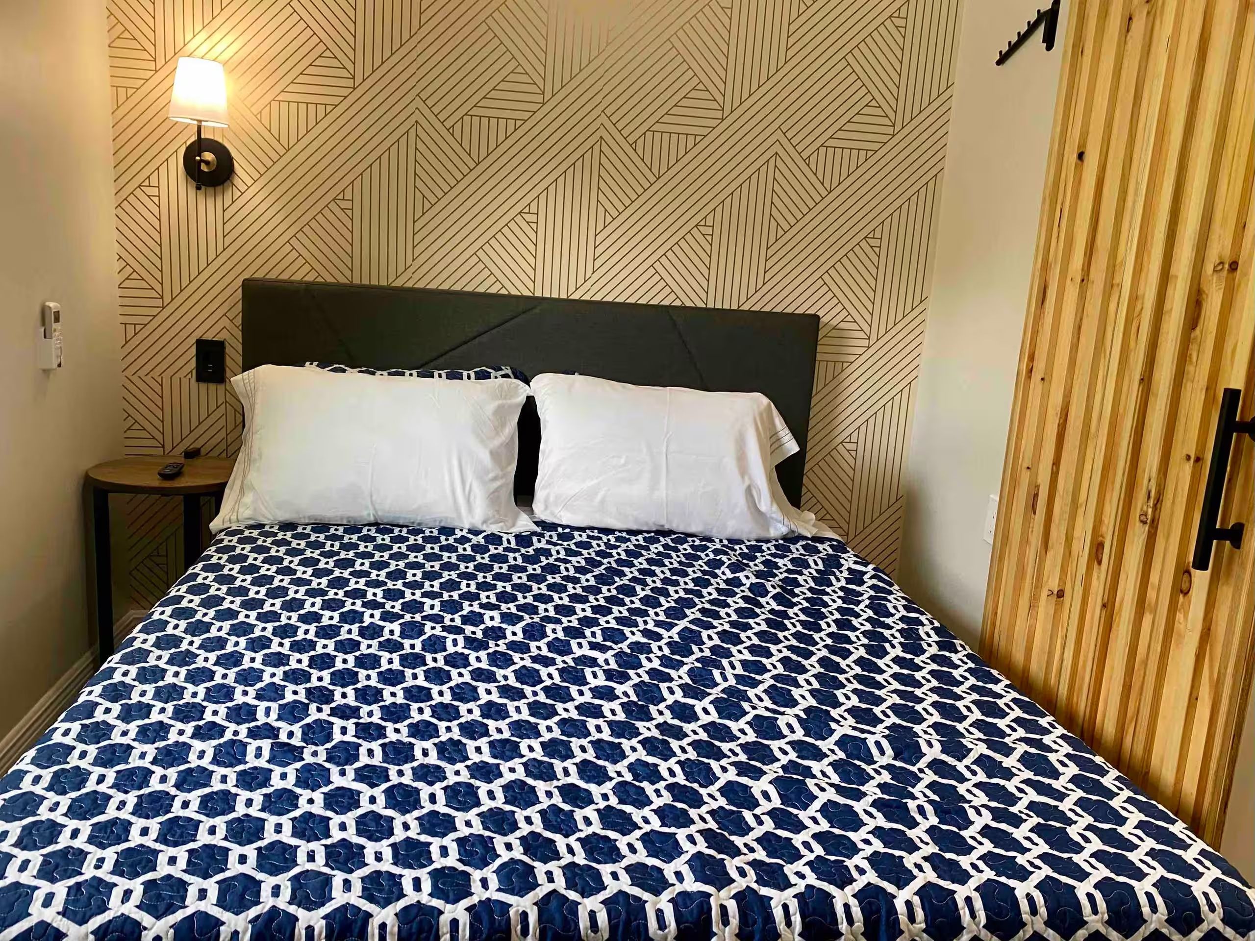Ein Bett mit einem geometrisch gemusterten Überwurf, einem Kopfteil und einer Wand mit geometrischem Muster.