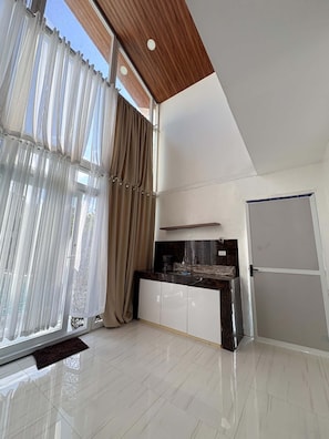 A modern kitchen with a marble countertop, a built-in oven, and a stainless steel refrigerator.