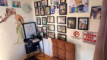 A room with a wall decorated with framed photos, a blackboard, and a sign prohibiting smoking.