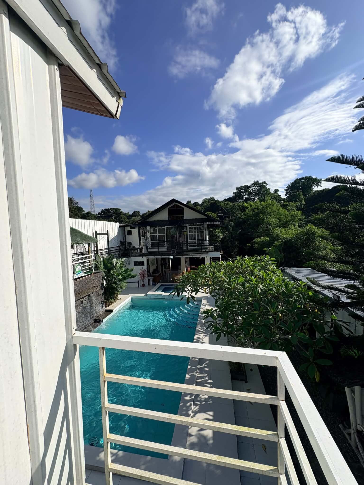 A residential property with a swimming pool, a two-story house, and a lush garden.