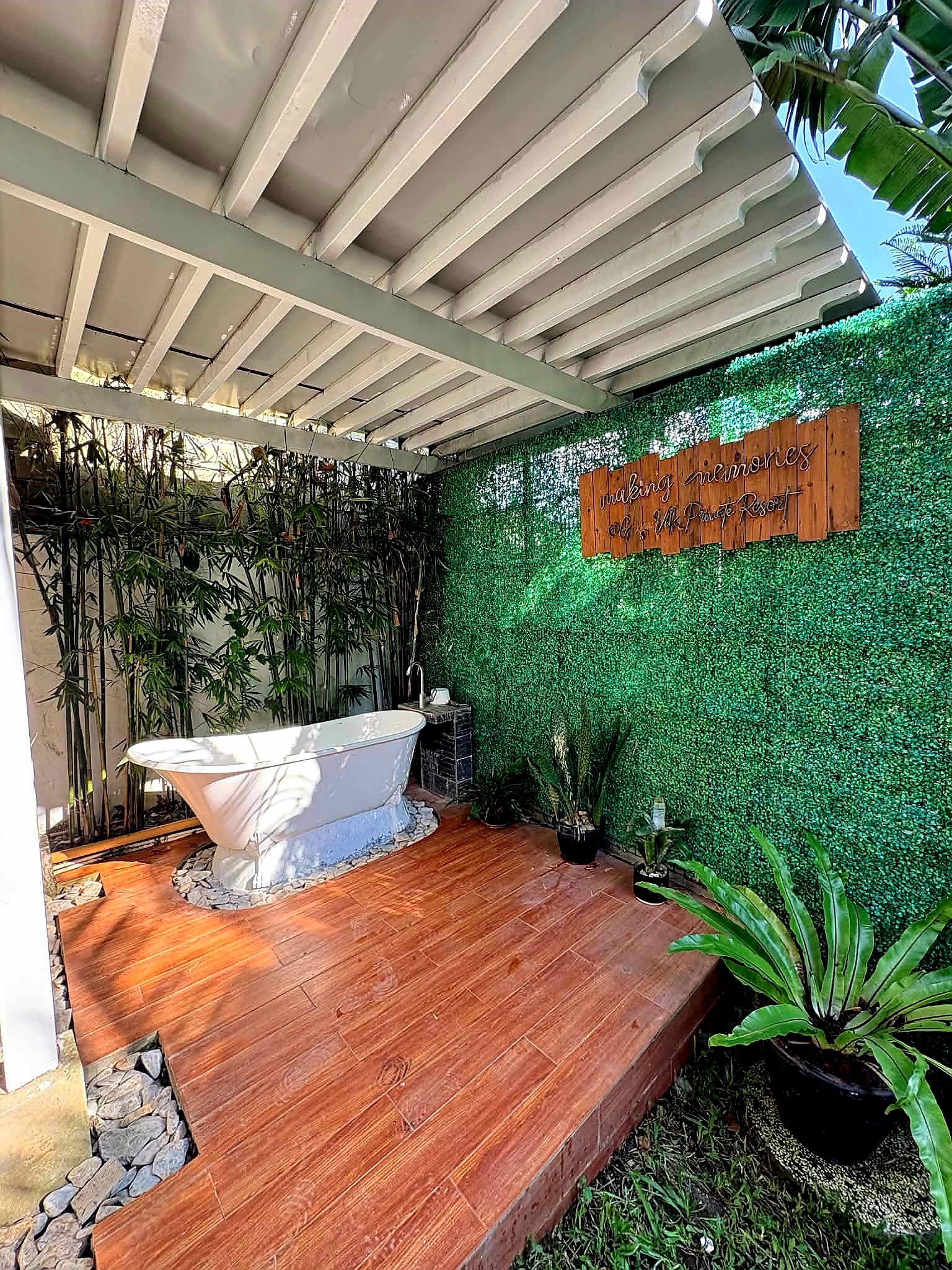Un área de spa con una bañera independiente, plantas de bambú y un letrero que dice 'making memories'.