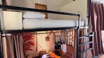 A bunk bed room with a ladder, a small table, and a wall of framed photos.