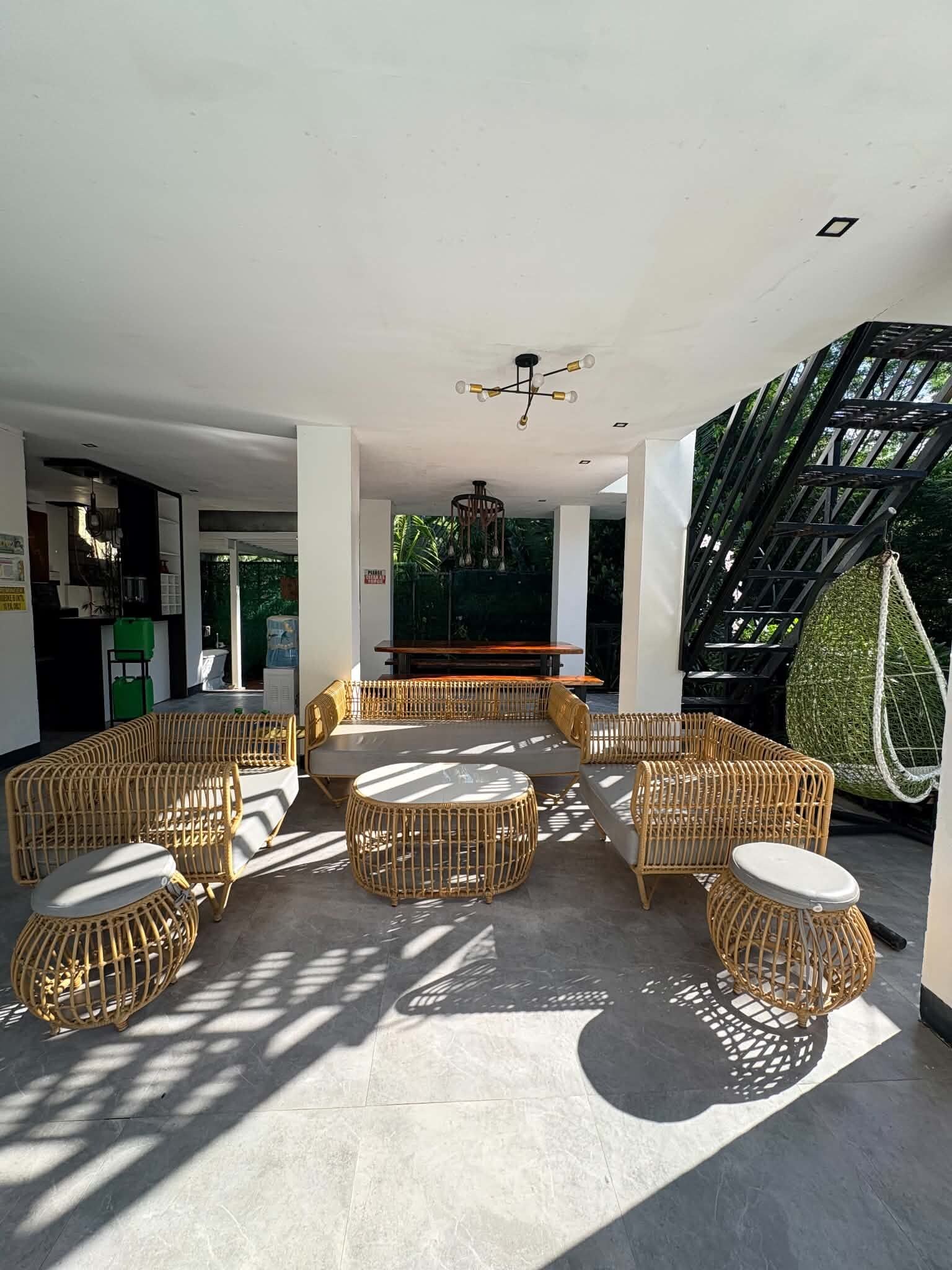 A spacious indoor area with wicker furniture, a bar, and a staircase leading outside.