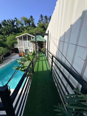 A pool area with a clear view of the sky, a white building, and lush greenery. - Green Villa Private Resort Tropical Luxury, Private Pool & Nature Escape (Cavite)