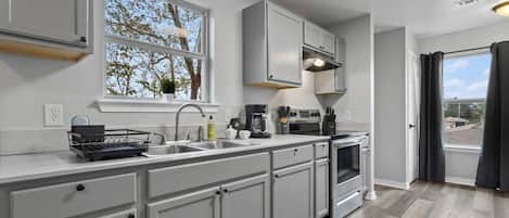 A modern kitchen with a large window, built-in appliances, and a view of the outdoors.