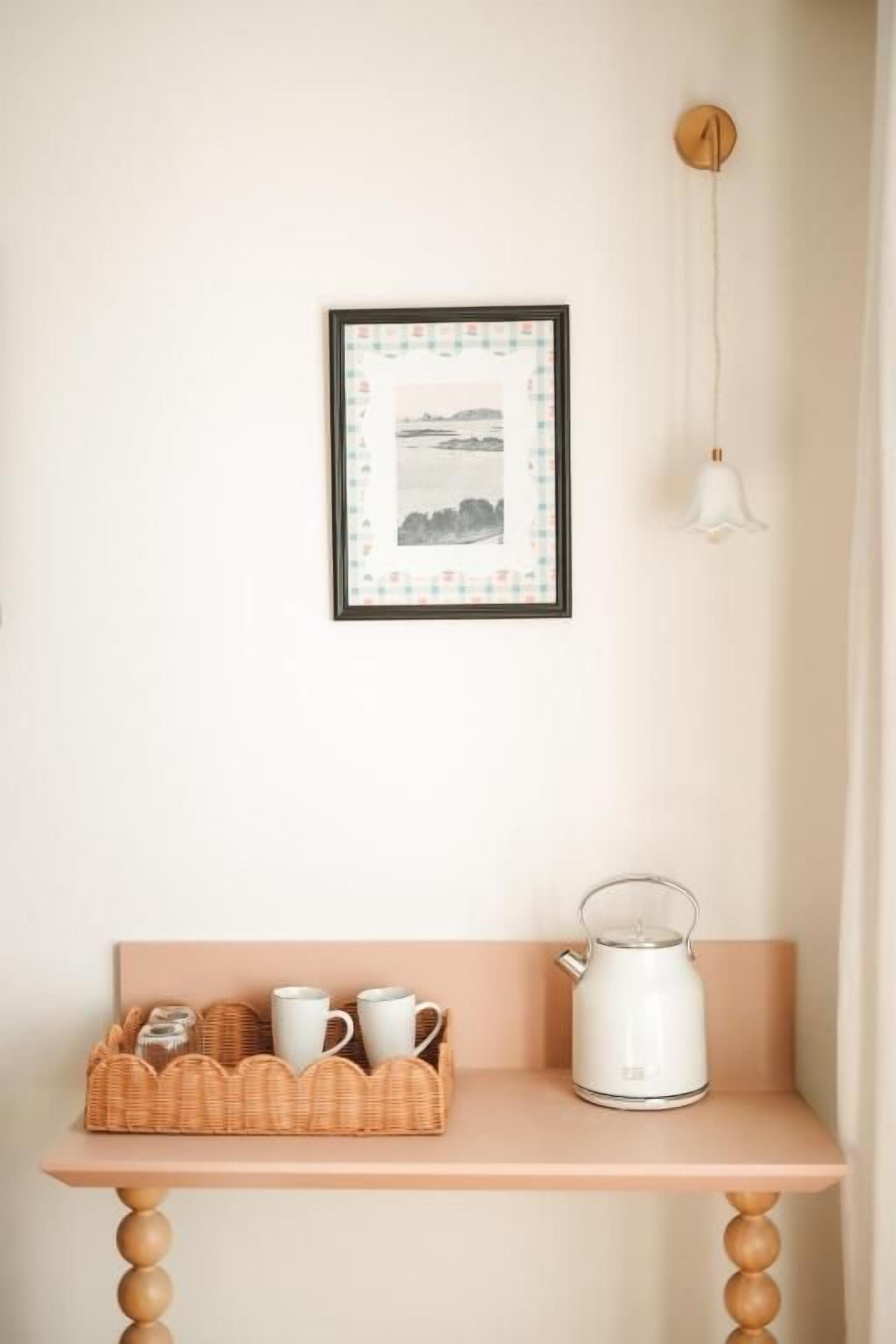 Una habitación con una mesa de madera, una tetera blanca y una cesta de mimbre con tazas y una tetera.