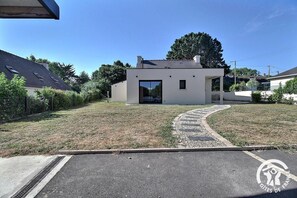 Edifici modern amb teulada plana, gran porta de vidre i un vial pavimentat que condueix a l'entrada.