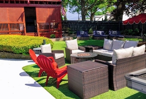 An outdoor patio area with wicker furniture, a red chair, and a fire pit. - PC+Downtown 13 Beds 3 full Baths (Providence)