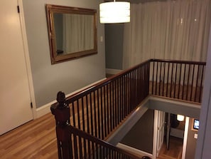 A staircase with a wooden railing, a mirror on the wall, and a light fixture above. - PC+Downtown 13 Beds 3 full Baths (Providence)