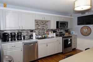 A modern kitchen with white cabinets, stainless steel appliances, and a tiled backsplash. - PC+Downtown 13 Beds 3 full Baths (Providence)
