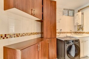 A modern kitchen with wooden cabinets, a washing machine, and a tiled backsplash. - New Listing (Bogotá)