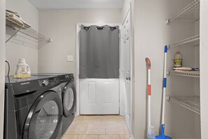 A laundry room with a Samsung washing machine, a mop, and cleaning supplies. - Aladdin Themed Condo Near Base and the Beach (Biloxi)