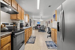 A modern kitchen with wooden cabinets, stainless steel appliances, and a dining area with a table and chairs. - Aladdin Themed Condo Near Base and the Beach (Biloxi)