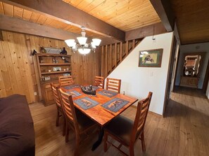 A wooden dining room with a table set for six, a chandelier, and a staircase leading to another level. - Enjoy an Escape at Big Bear Lake (Big Bear Lake)