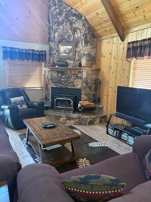 A cozy living room with a stone fireplace, leather sofa, and a flat-screen TV. - Enjoy an Escape at Big Bear Lake (Big Bear Lake)