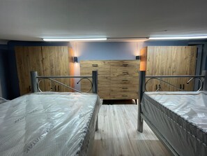 A bedroom with two beds, wooden wardrobe, and wall-mounted lights. - KADIKÖY MERKEZDE (İstanbul)