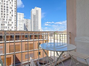 Ein Balkon mit Tisch und Stühlen mit Blick auf eine Skyline und hohe Gebäude.