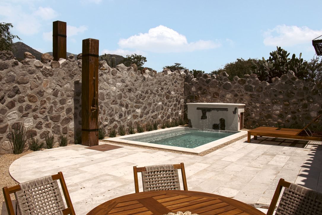 A stone wall, a pool, and outdoor furniture.