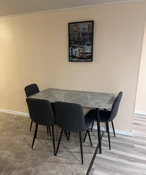 Ein Konferenzraum mit einem Marmortisch und schwarzen Stühlen, einem gerahmten Bild an der Wand und einem gefliesten Boden.