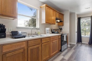 A modern kitchen with wooden cabinets, a stainless steel sink, and an oven. - Dreamworks Themed Beach Escape (Biloxi)