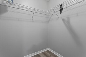 Un coin de pièce avec une étagère en fil de métal et un mur blanc.