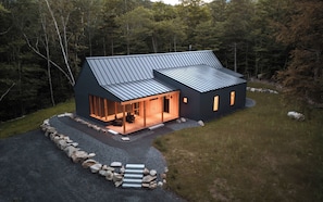 A modern house with a sloped roof, large windows, and a stone pathway leading to the entrance. - NEW Cozy home located within minutes to Sugarloaf (Carrabassett Valley)