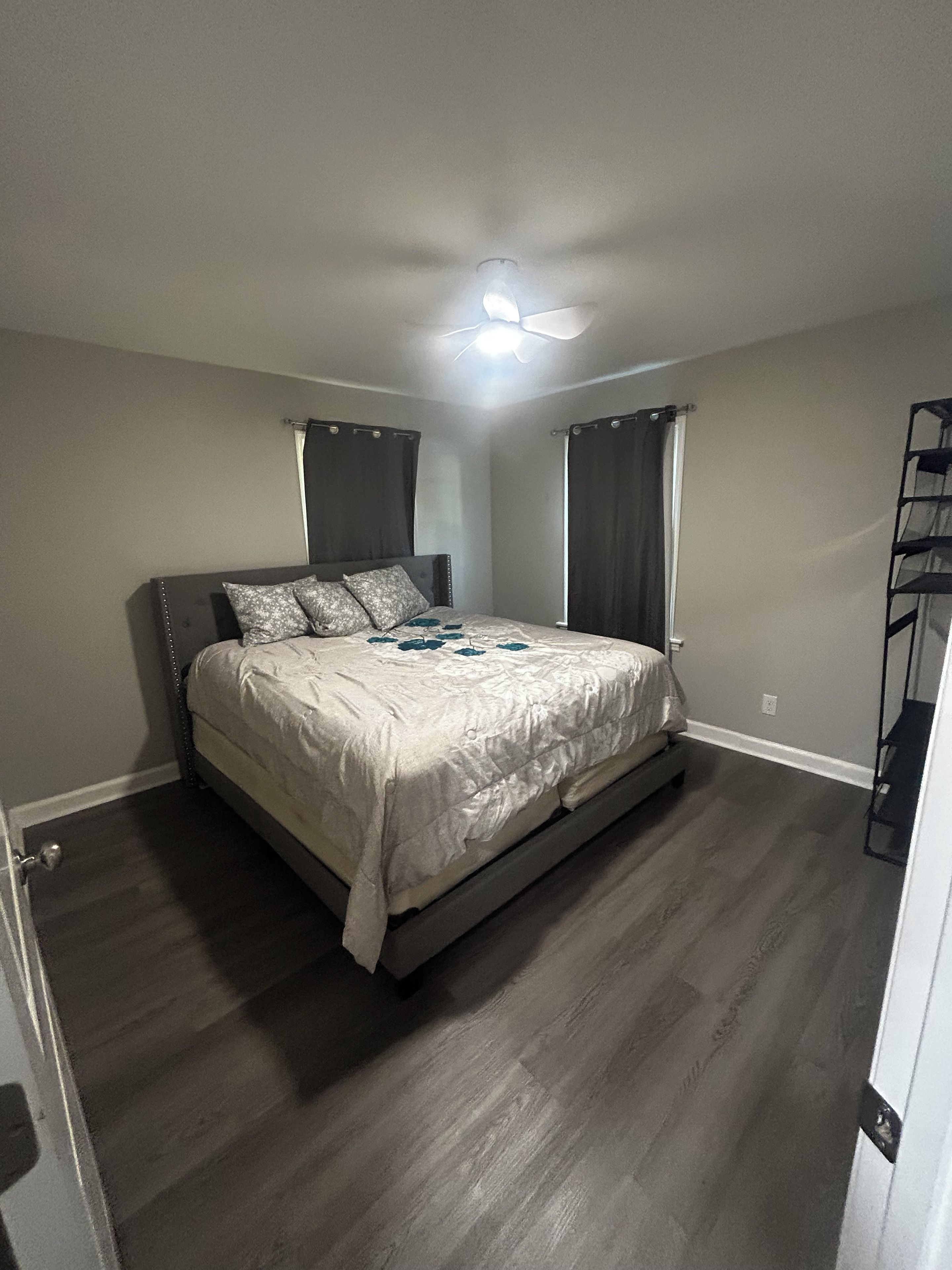 A bedroom with a bed, a ceiling fan, and a built-in shelf unit.