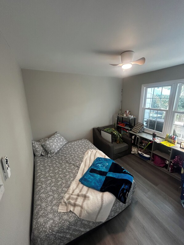 A compact room with a bed, a desk, and a window.