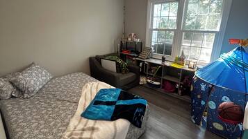 A bedroom with a bed, a desk, and a window.