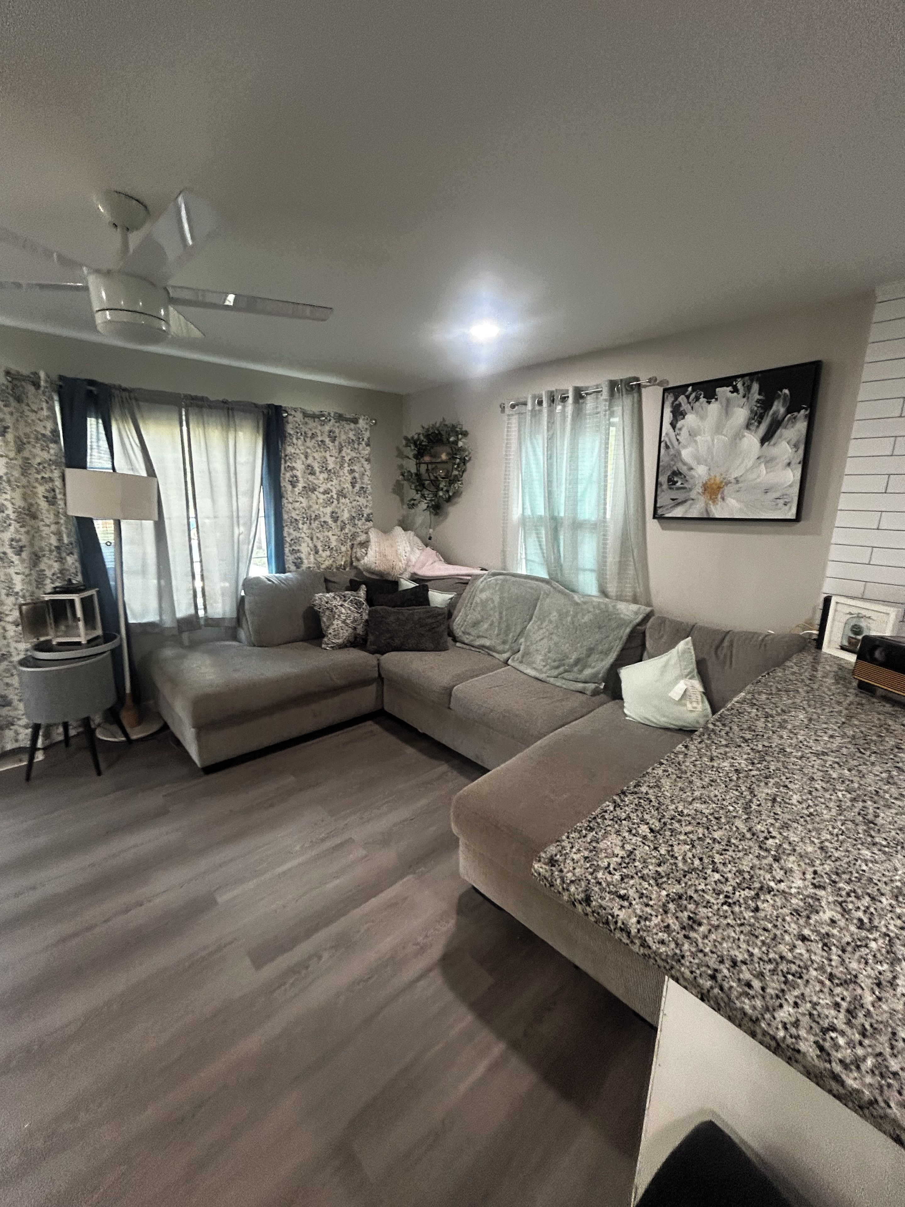 A modern living room with a sectional sofa, a small side table, and a large window with curtains.