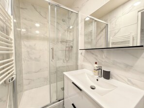 Une salle de bain moderne avec une douche à parois de verre, un lavabo blanc et un miroir au-dessus.
