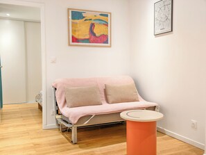 Habitació amb un llit, una taula petita i dues pintures penjades a la paret.