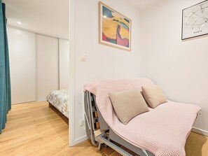 A bedroom with a bed, pillows, a wall-mounted map, and a door leading to another room. - New Listing (Paris)