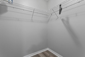 A corner of a room with a metal wire shelf and a white wall. - Super Mario Beach Escape (Biloxi)