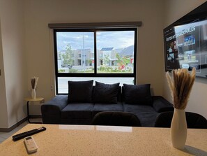 A modern living room with a large window, a sofa, a coffee table, and a flat-screen TV mounted on the wall. - New Listing (Juárez)