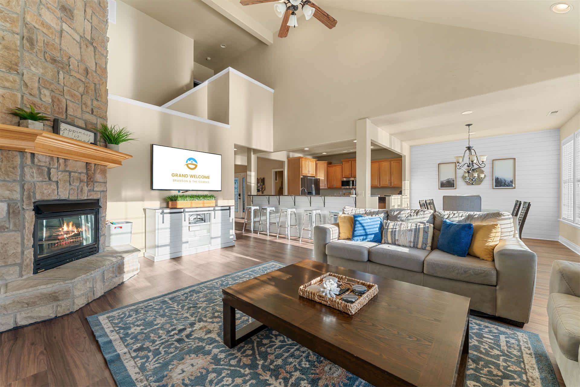 A spacious living room with a fireplace, a sofa, a coffee table, and a kitchen in the background.