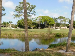 A golf course with a pond, trees, and buildings in the background. - Welcoming 1-bedroom condo in sunny Sarasota with lake views! (Sarasota)